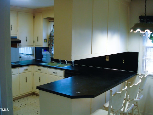 kitchen with white cabinetry, kitchen peninsula, sink, and extractor fan