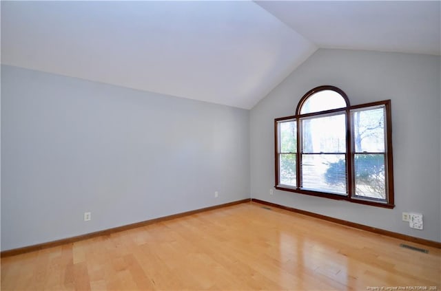 empty room featuring lofted ceiling and light wood-type flooring