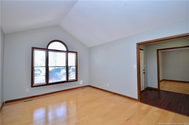 spare room featuring light hardwood / wood-style flooring and vaulted ceiling