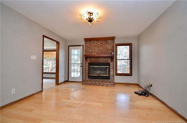 unfurnished living room featuring a brick fireplace and light wood-type flooring