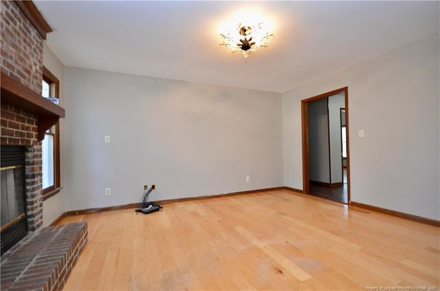 unfurnished living room with a healthy amount of sunlight, a brick fireplace, and light wood-type flooring