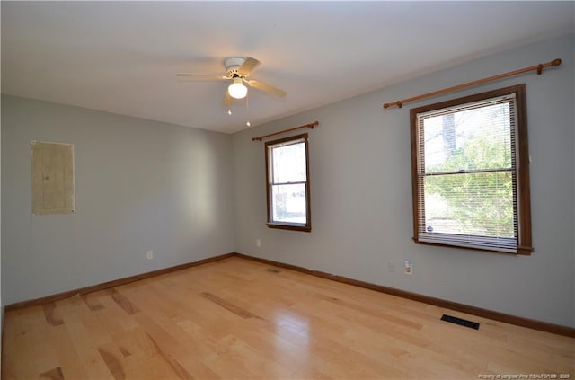 empty room featuring ceiling fan, electric panel, and light hardwood / wood-style flooring