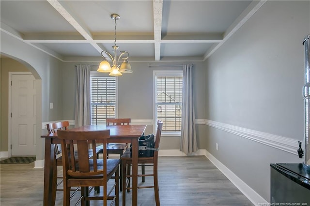 dining area featuring beamed ceiling, wood-type flooring, coffered ceiling, and a chandelier