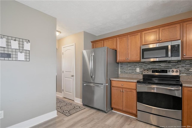 kitchen featuring tasteful backsplash, light hardwood / wood-style floors, a textured ceiling, and appliances with stainless steel finishes