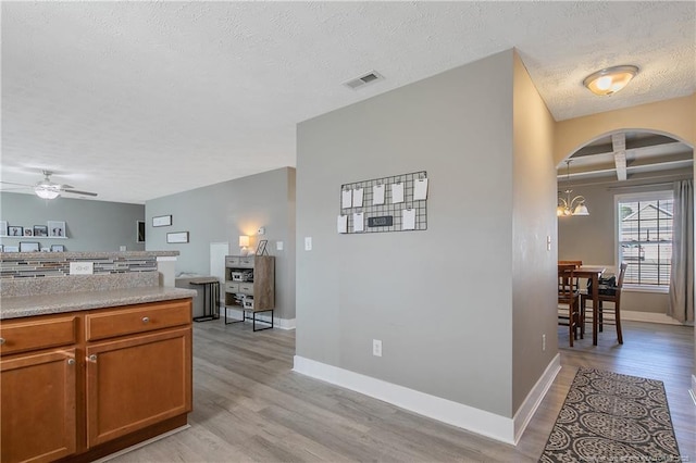 kitchen featuring ceiling fan with notable chandelier, a textured ceiling, and light hardwood / wood-style floors