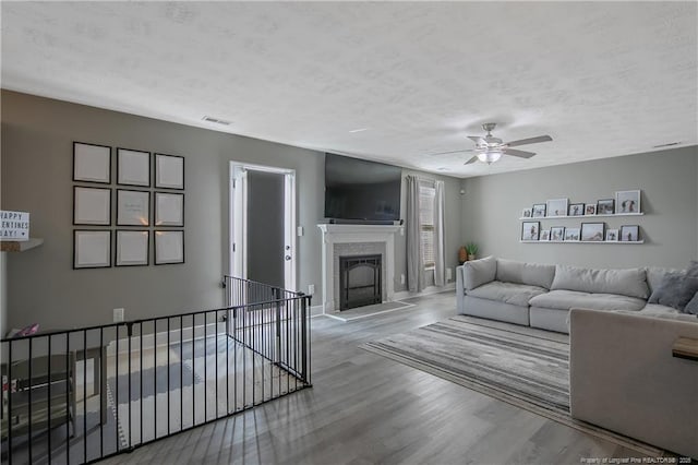 living room featuring ceiling fan, hardwood / wood-style floors, and a textured ceiling