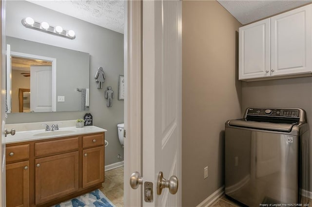 interior space with light tile patterned floors, sink, cabinets, a textured ceiling, and washer / clothes dryer