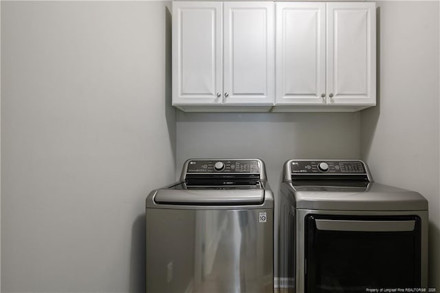 clothes washing area featuring cabinets and separate washer and dryer