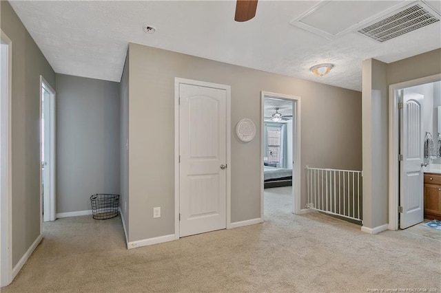 unfurnished bedroom with connected bathroom, light carpet, and a textured ceiling