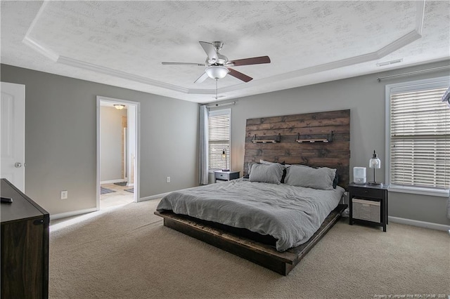 bedroom with ceiling fan, a tray ceiling, light colored carpet, and a textured ceiling