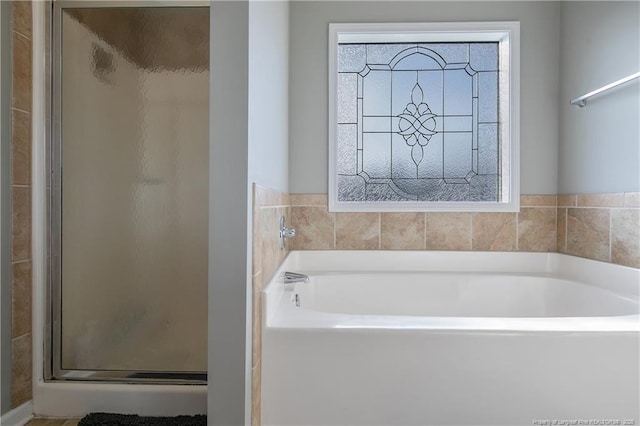 bathroom with plenty of natural light and separate shower and tub