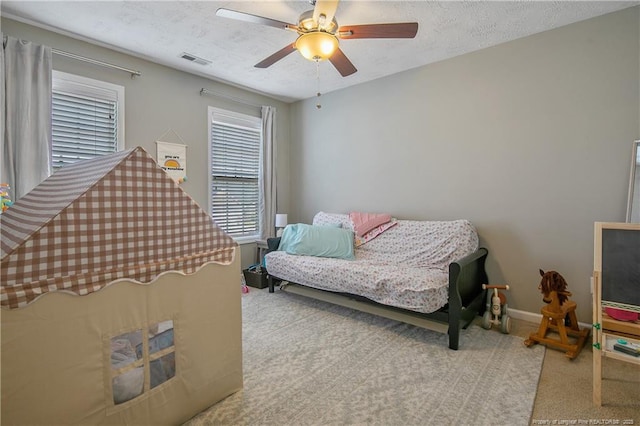 carpeted bedroom featuring ceiling fan and a textured ceiling