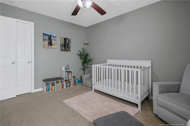 bedroom with ceiling fan, carpet, and a crib