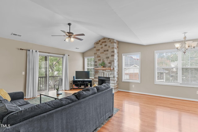 living room with lofted ceiling, ceiling fan with notable chandelier, a fireplace, and light wood-type flooring