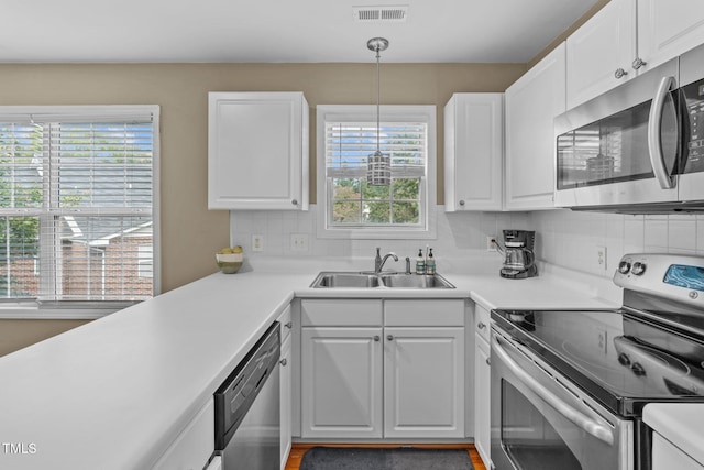 kitchen with stainless steel appliances, sink, hanging light fixtures, and white cabinets