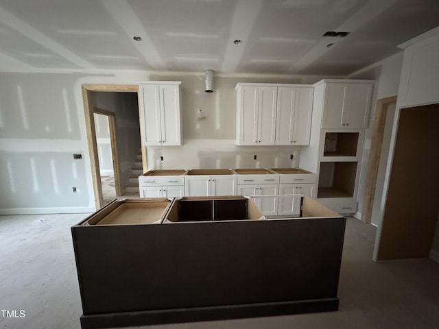 kitchen featuring concrete floors, a center island, and white cabinets