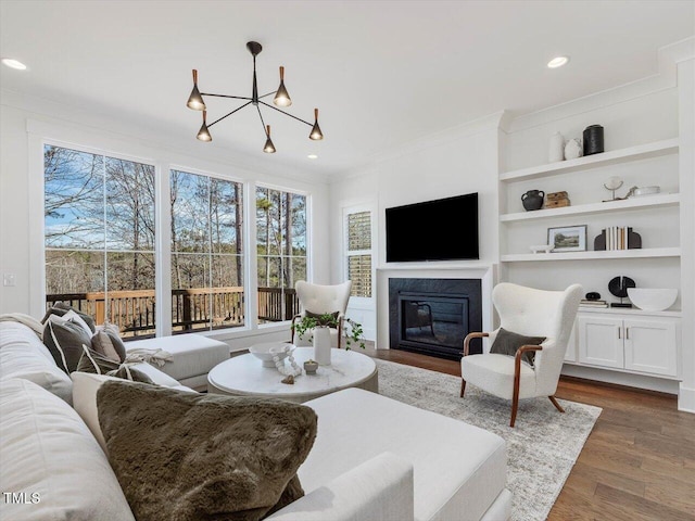 living room featuring crown molding, dark hardwood / wood-style flooring, and built in shelves