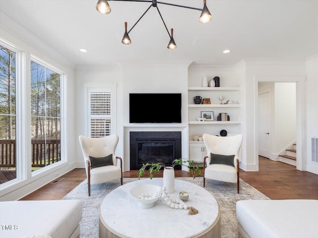 living room with crown molding, built in features, and hardwood / wood-style flooring