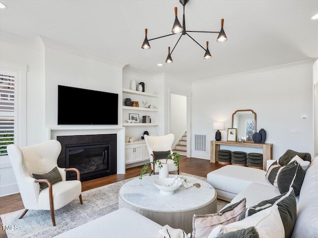 living room with an inviting chandelier, hardwood / wood-style flooring, and ornamental molding