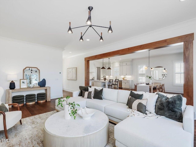 living room with hardwood / wood-style flooring, ornamental molding, and a notable chandelier