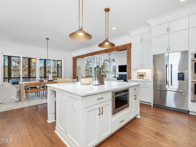 kitchen with white cabinetry, hanging light fixtures, stainless steel appliances, and a kitchen island