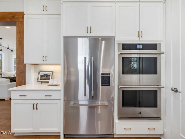 kitchen featuring tasteful backsplash, appliances with stainless steel finishes, and white cabinets