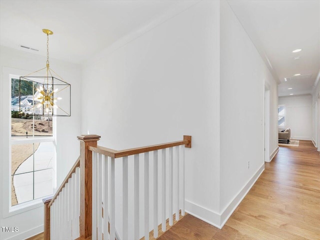 hallway featuring an inviting chandelier and light hardwood / wood-style flooring