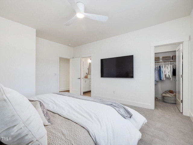 bedroom featuring connected bathroom, a spacious closet, light colored carpet, a closet, and ceiling fan