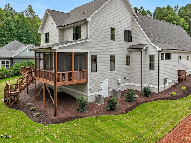 rear view of property featuring cooling unit, a sunroom, and a lawn