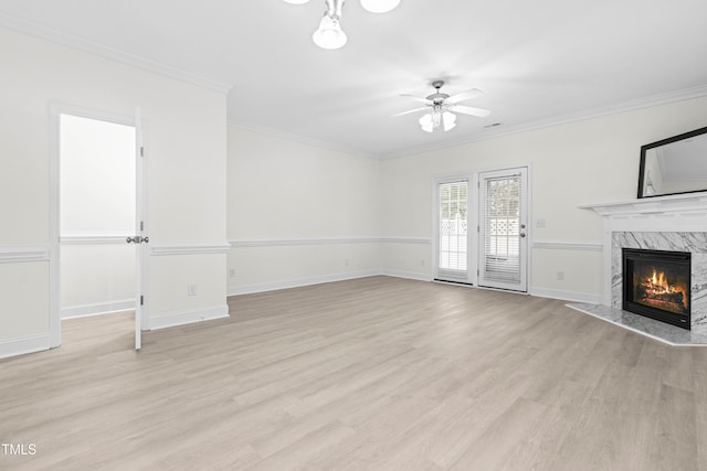 unfurnished living room featuring a high end fireplace, ornamental molding, light hardwood / wood-style floors, and ceiling fan