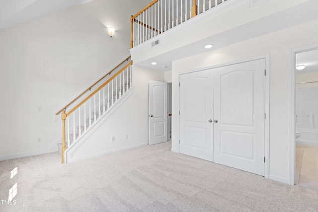 interior space with light carpet and a high ceiling