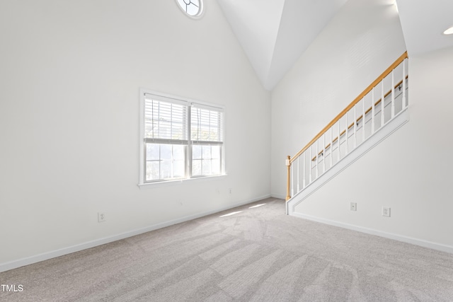 unfurnished living room featuring high vaulted ceiling and carpet floors