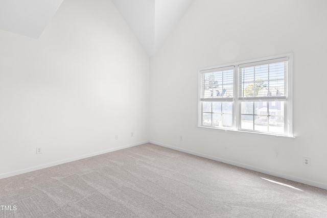 carpeted spare room with vaulted ceiling