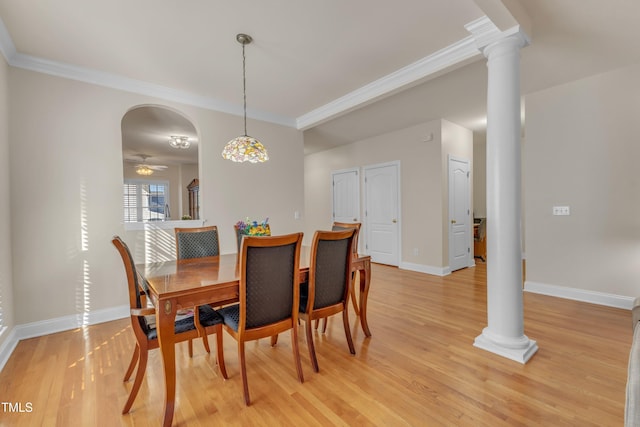 dining room featuring arched walkways, light wood-style flooring, decorative columns, and crown molding