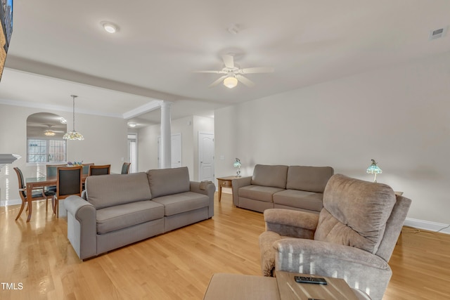 living room featuring light wood finished floors, decorative columns, visible vents, baseboards, and a ceiling fan