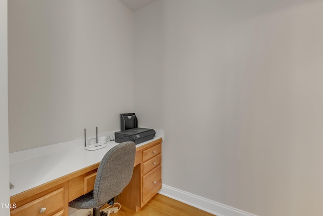 home office with baseboards, light wood finished floors, and built in study area