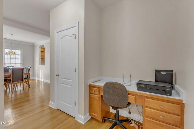 home office with arched walkways, light wood finished floors, ornamental molding, and baseboards