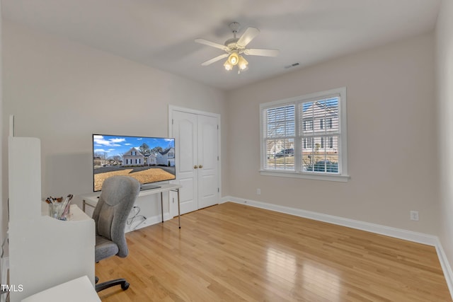 office space featuring baseboards, a ceiling fan, visible vents, and light wood-style floors