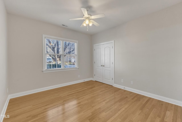 unfurnished bedroom with a closet, light wood-type flooring, visible vents, and baseboards