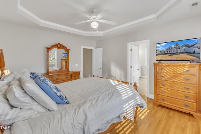 bedroom featuring a tray ceiling, visible vents, ceiling fan, light wood-type flooring, and baseboards