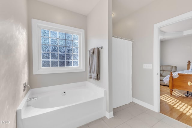 full bathroom featuring tile patterned flooring, connected bathroom, baseboards, and a bath