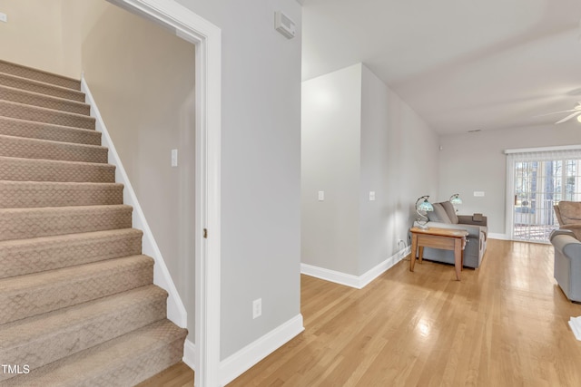 stairway with a ceiling fan, baseboards, and wood finished floors