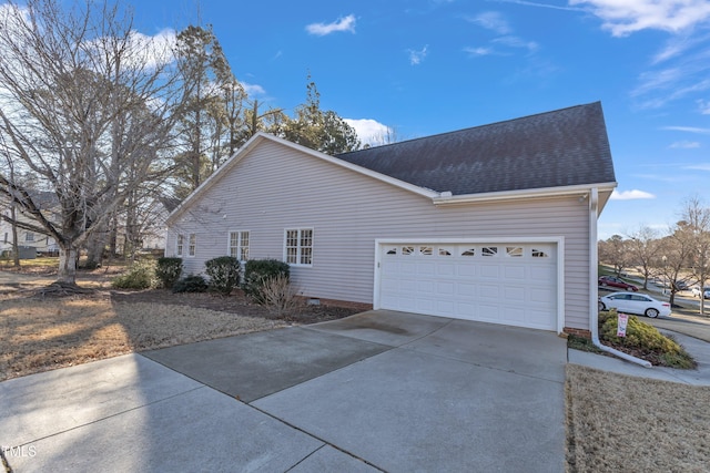 view of side of home with concrete driveway, roof with shingles, and an attached garage