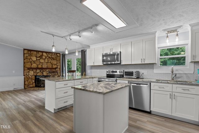 1167 John D Winstead Rd, Roxboro, NC 27574 - kitchen with stainless steel appliances, a sink, a textured ceiling, a peninsula, and wood finished floors