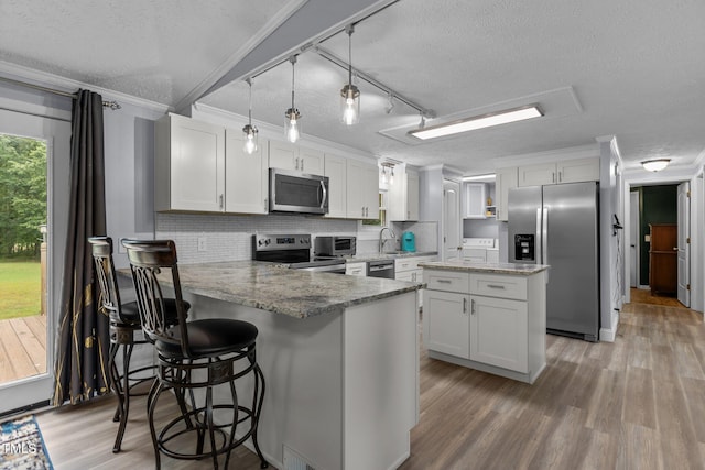 1167 John D Winstead Rd, Roxboro, NC 27574 - kitchen featuring appliances with stainless steel finishes, a textured ceiling, crown molding, a peninsula, and decorative backsplash