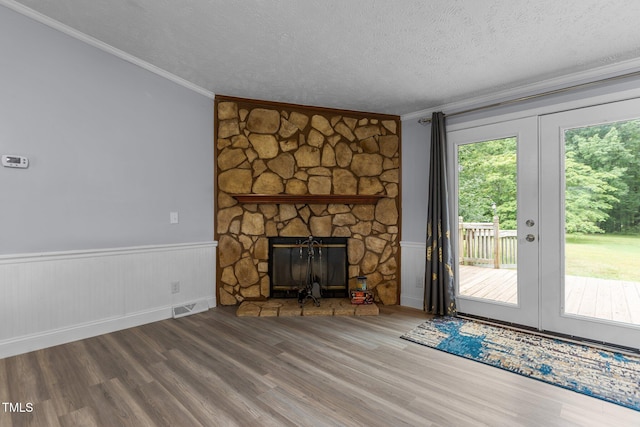 1167 John D Winstead Rd, Roxboro, NC 27574 - unfurnished living room featuring ornamental molding, a stone fireplace, wood finished floors, a textured ceiling, and french doors