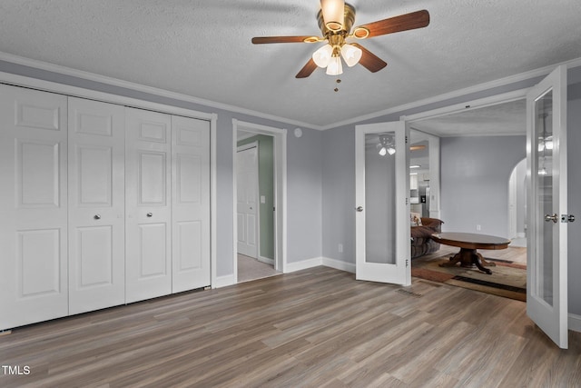 1167 John D Winstead Rd, Roxboro, NC 27574 - unfurnished bedroom with light wood-type flooring, baseboards, arched walkways, french doors, and a textured ceiling