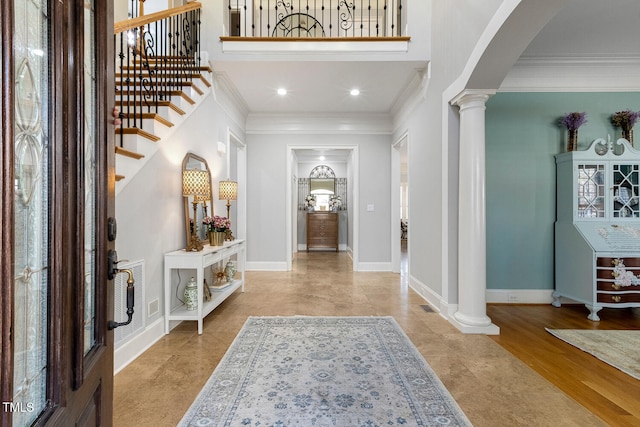 entryway featuring crown molding, a high ceiling, and ornate columns