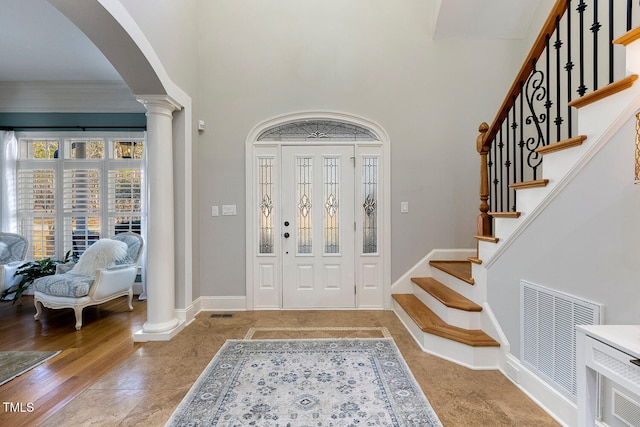 foyer entrance with decorative columns and a high ceiling