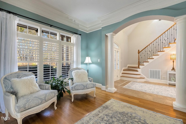 living area featuring crown molding, decorative columns, and hardwood / wood-style floors